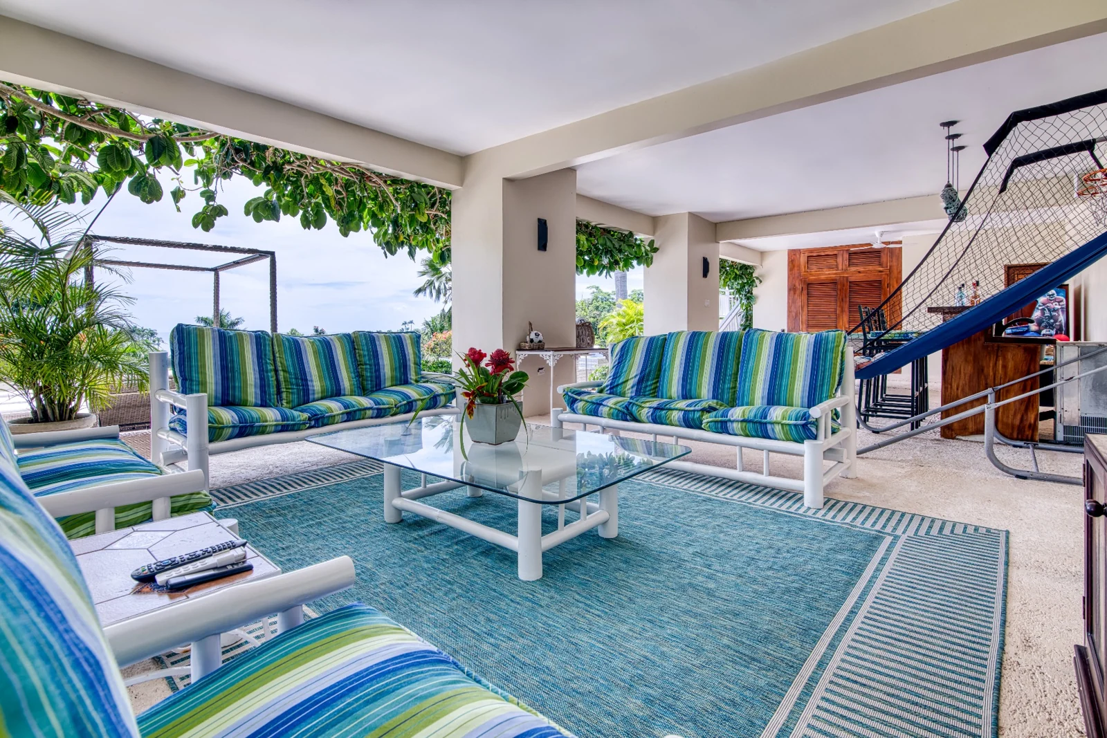 Shaded veranda seating overlooking tropical gardens and the ocean